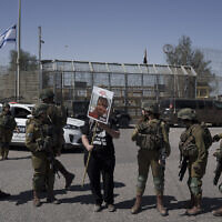 A woman holds up a picture of a hostage held captive by Hamas in the Gaza Strip as she stands next to Israeli soldiers at Israel's Nitzana border crossing with Egypt in southern Israel, Tuesday, March 5, 2024, protesting against the delivery of humanitarian aid to the Gaza Strip until all hostages are released. (AP/Leo Correa)