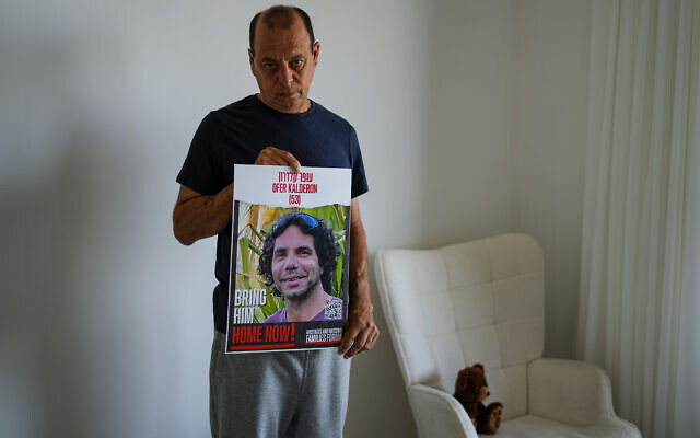 Nissan Kalderon poses with a photo of his only brother, Ofer, a hostage held in the Gaza Strip by the Hamas terror group, in Ramat Gan, March 13, 2024 (AP Photo/Ariel Schalit)