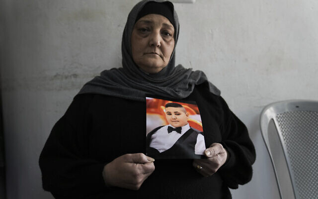 Rawiya Halhouli holds a photo of her slain son Rami Halhouli, in their house in Shuafat refugee camp in east Jerusalem, March 17, 2024. (AP Photo/Mahmoud Illean)