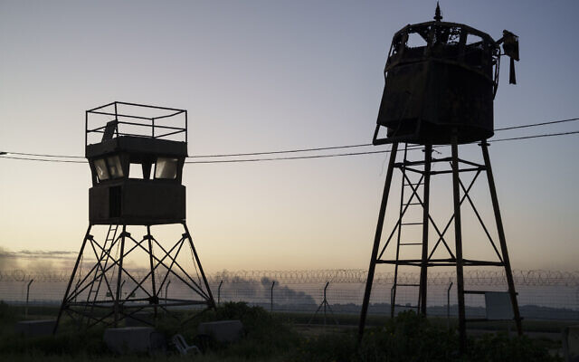 An old observation towers stand near a fence as smoke rises after an explosion in the Gaza Strip, seen from Kibbutz Nahal Oz, Feb. 28, 2024. (AP Photo/Leo Correa)