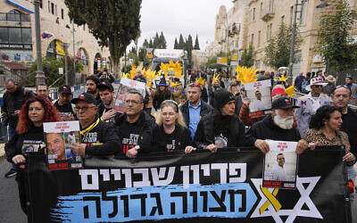 Relatives and supporters of Israeli hostages held in the Gaza Strip by the Hamas terror group lead a Purim parade in Jerusalem, March 25, 2024. The banner, a reference to the imperatives to see the hostages released, literally translates as: Redeeming the captives is a great commandment. Jerusalem Mayor Moshe Lion is third from left. (AP Photo/Ohad Zwigenberg)