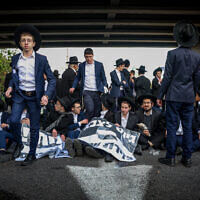 Ultra-Orthodox Jews block a road during a protest against drafting of Haredim to the IDF, on Route 4 near Bnei Brak, March 3, 2024. (Itai Ron/Flash90)