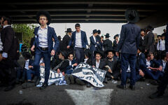 Ultra-Orthodox Jews block a road during a protest against drafting of Haredim to the IDF, on Route 4 near Bnei Brak, March 3, 2024. (Itai Ron/Flash90)