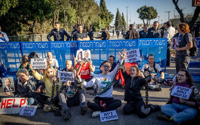 Activists chain themselves together as they block a road outside the Knesset in Jerusalem during a protest against the current Israeli government, March 20, 2024. (Yonatan Sindel/Flash90)