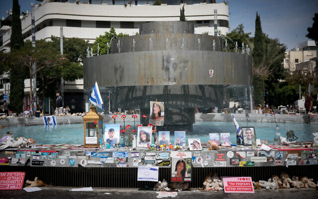 Israelis walk past candles and photographs of the victims murdered and held hostage by Hamas terrorists in Gaza since October 7, on Dizengoff Square in Tel Aviv. March 21, 2024. (Miriam Alster/FLASH90)
