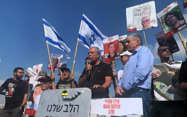 Mickey Levy speaks to marchers from stage outside Mevaseret Zion mall on last day of hostage families' unity march to Jerusalem on March 2, 2024. (Charlie Summers/Times of Israel)