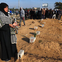 Illustrative - A Palestinian woman prays by a relative's tomb as others bury their dead following overnight Israeli airstrikes, at a cemetery in east Khan Younis in the southern Gaza Strip, February 26, 2024. (Photo by SAID KHATIB / AFP)