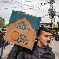 A man carries a cardboard box of food aid provided by World Central Kitchen in Rafah in the southern Gaza Strip on March 17, 2024. (Mohammed Abed/AFP)