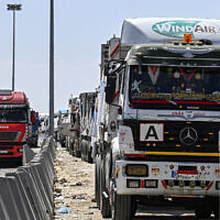 File: Egyptian trucks carrying humanitarian aid bound for the Gaza Strip queue outside the Egyptian side of the Rafah border crossing into the enclave, March 23, 2024. (Khaled Desouki/AFP)