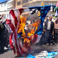 Illustrative: Demonstrators burn a US and an Israeli flag during the funeral for seven Islamic Revolutionary Guard Corps members killed in a strike in Syria, which Iran blamed on Israel, in Tehran on April 5, 2024. (Atta Kenare / AFP)