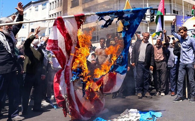 Illustrative: Demonstrators burn a US and an Israeli flag during the funeral for seven Islamic Revolutionary Guard Corps members killed in a strike in Syria, which Iran blamed on Israel, in Tehran on April 5, 2024. (Atta Kenare / AFP)