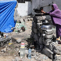 A woman washes pots outside a tent pitched by a destroyed building in Rafah in the southern Gaza Strip on April 5, 2024. (Mohammed Abed / AFP)