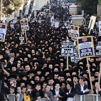 Ultra-Orthodox Jewish men and youth raise placards during a protest against Israeli army conscription outside an army recruitment office in Jerusalem on April 11, 2024. (Menahem Kahana / AFP)