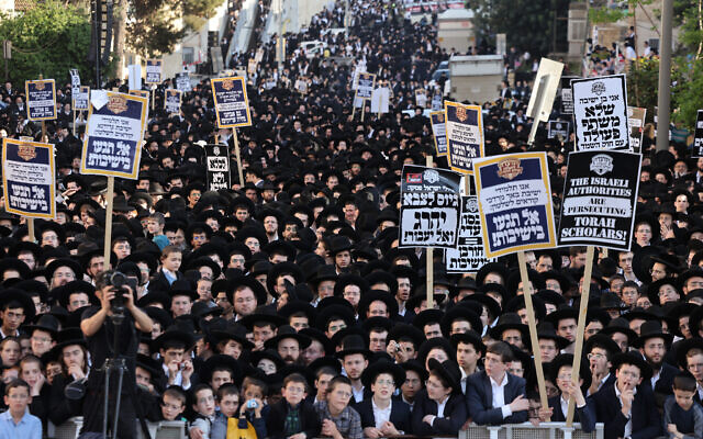 Ultra-Orthodox Jewish men and youth raise placards during a protest against Israeli army conscription outside an army recruitment office in Jerusalem on April 11, 2024. (Photo by Menahem Kahana / AFP)