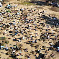 In this aerial view people walk past portraits of people who were taken hostage or killed in the Hamas attack on the Supernova music festival on October 7, at the site of the festival near Kibbutz Reim in southern Israel on April 10, 2024. (JACK GUEZ / AFP)