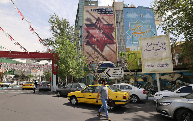 Iranians walk next to a Hebrew-language poster asking Israelis if they have stockpiled enough food in their bomb shelters, in Tehran on April 13, 2024. (ATTA KENARE / AFP)