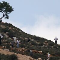 File: Armed settlers gather on a hill overlooking the village of al-Mughayyir near Ramallah in the West Bank on April 13, 2024 (JAAFAR ASHTIYEH / AFP)
