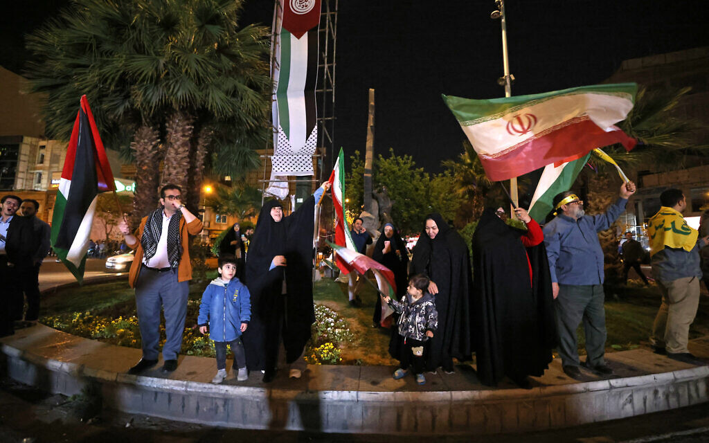 A group of demonstrators wave Iran's flag and Palestinian flags at Palestine Square in Tehran early on April 14, 2024, after Iran launched a drone and missile attack on Israel. (Atta Kenare/AFP)