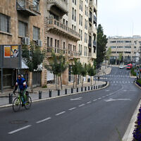 A man rides a bicycle along a Jerusalem street on April 14, 2024. (Ronaldo Schemidt/AFP)