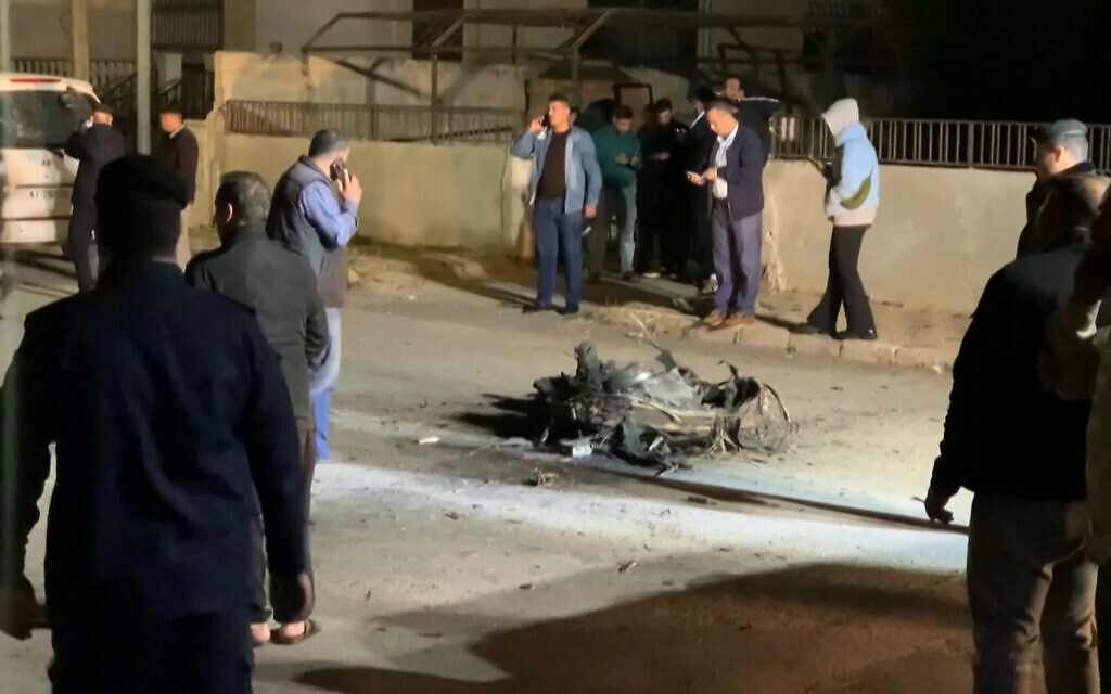 An image grab from AFPTV footage shows Jordanian onlookers and security agents standing around the debris of a missile intercepted over Amman amid an unprecedented Iranian drone and missile attack on Israel, April 14, 2024 (Ahmad SHOURA / AFP)