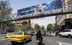 A banner depicting the mythical Persian hero Arash the archer firing a missile from his bow, with text in Persian reading 'I will not abandon my homeland,' hangs on a suspended pedestrian bridge crossing in central Tehran on April 15, 2024. (Atta Kenare/AFP)