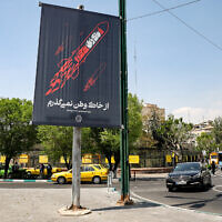 A banner depicting the a flying missile with text in Persian reading "I will not abandon my homeland" is displayed along a street in central Tehran on April 15, 2024.  (Photo by ATTA KENARE / AFP)