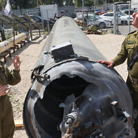 Israeli military spokesman Rear Admiral Daniel Hagari, right, and his deputy Masha Michelson pose next to an Iranian ballistic missile which was intercepted and fell into the Dead Sea days earlier, during a media tour at the Julis military base near the southern Israeli city of Kiryat Malachi on April 16, 2024. (Gil Cohen-Magen/AFP)