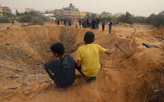 Two Palestinian boys look at a huge crater following an overnight Israeli strike in Rafah in the southern Gaza Strip on April 18, 2024 (Photo by MOHAMMED ABED / AFP)