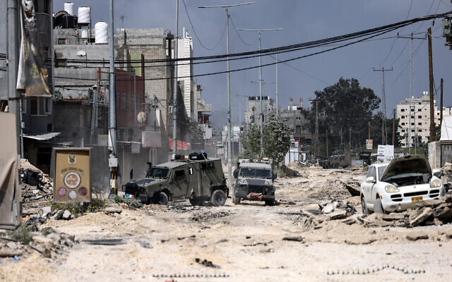 Israeli military vehicles drive along a devastated street in the Nur Shams refugee camp in the West Bank, during a raid on April 19, 2024. (Jaafar Ashtiyeh/AFP)