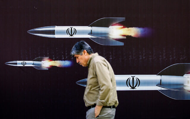Illustrative: A man walks past a banner depicting missiles along a street in Tehran on April 19, 2024. (AFP)
