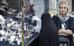 Iranians walk past shops in the capital Tehran on April 21, 2024. (Photo by ATTA KENARE / AFP)