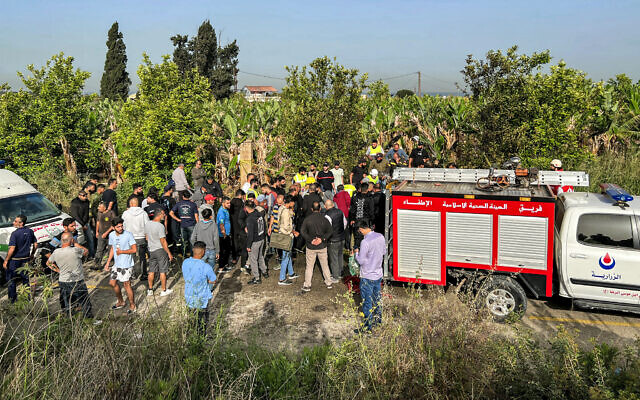 People gather at the site of an alleged Israeli strike on a vehicle in the Adloun plain area, between Lebanon's southern cities of Sidon and Tyre, on April 23, 2024 (Mahmoud ZAYYAT / AFP)