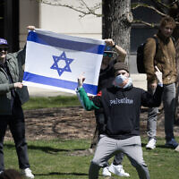 An anti-Israel protester gives the finger in front of counter-demonstrators holding an Israeli flag outside the Gaza Solidarity Encampment on the campus of Northwestern University on April 25, 2024 in Evanston, Illinois. (Scott Olson/Getty Images/AFP)