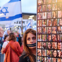 A protester with a zipper over her mouth holds a poster showing pictures of Israeli hostages taken captive by Hamas and other terrorists in Gaza during the October 7 attacks, during a demonstration calling for their release in the Israeli coastal city of Tel Aviv on April 27, 2024. (Jack Guez / AFP)