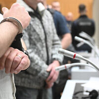 One of nine suspected participants in a coup plot wears handcuffs as he is brought to the courtroom to take the stand in the first set of proceedings in Stuttgart, southern Germany, on April 29, 2024. (Bernd Weißbrod/POOL/AFP)