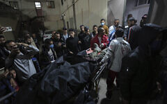 Palestinians carry the body of a person following an alleged Israeli airstrike, into the Al Aqsa hospital in Deir al Balah, Gaza Strip, Monday, April 1, 2024 (AP Photo/Abdel Kareem Hana)