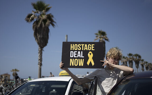 A protester holds a placard as relatives of hostages held in Gaza and their supporters block traffic outside of the US embassy, calling for the immediate release of all captives, Tel Aviv, April 12, 2024. (AP Photo/Maya Alleruzzo)