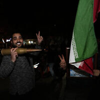 Iranian demonstrators flash the victory sign as they hold an Iranian flag and a model of a bullet during an anti-Israeli gathering at Palestine Square in Tehran, Iran, early Sunday, April 14, 2024. (AP Photo/Vahid Salemi)