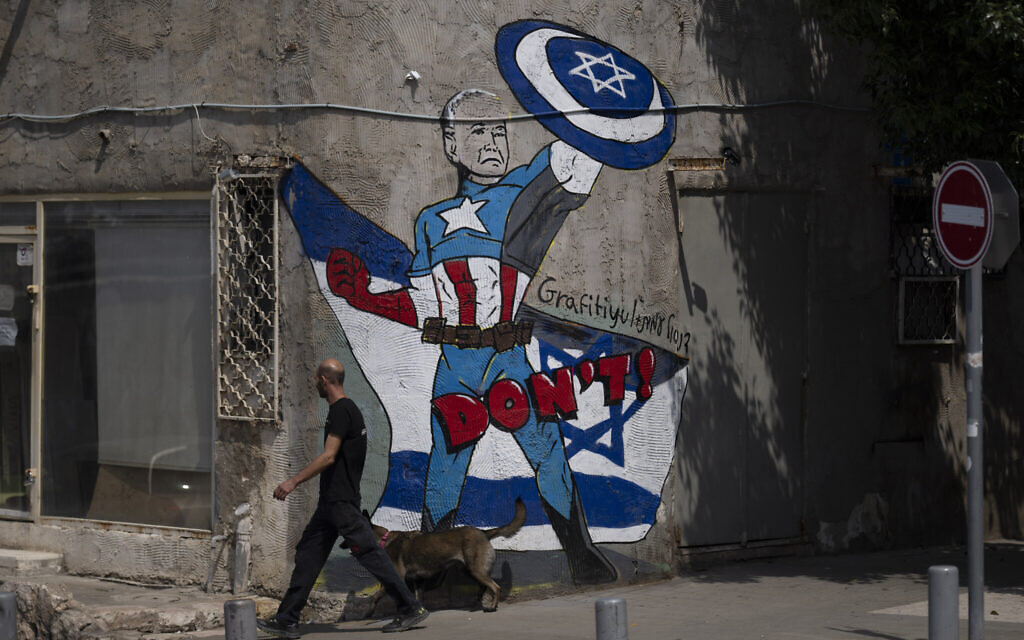 A man walks past a mural depicting US President Joe Biden as a superhero defending Israel on a street in Tel Aviv, April 14, 2024 (AP Photo/Leo Correa)