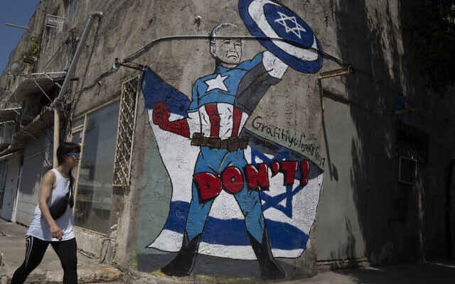A woman walks past a mural depicting US President Joe Biden as a superhero defending Israel on a street in Tel Aviv, Israel, Sunday, April 14, 2024. (AP Photo/Leo Correa)