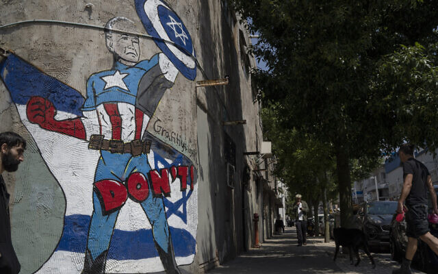 A man walks past a mural depicting the US President Joe Biden as a superhero defending Israel on a street in Tel Aviv, April 14, 2024. (AP Photo/Leo Correa)