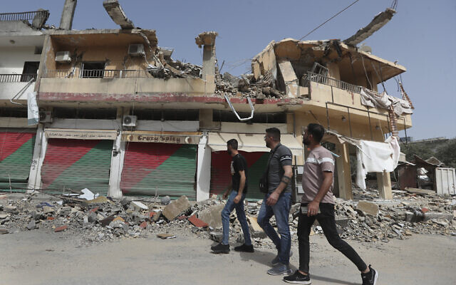 Lebanese villagers pass by a building which was destroyed by Israeli shelling, in Kfar Kila, a Lebanese border village with Israel, south Lebanon, April 18, 2024. (AP Photo/Mohammed Zaatari)