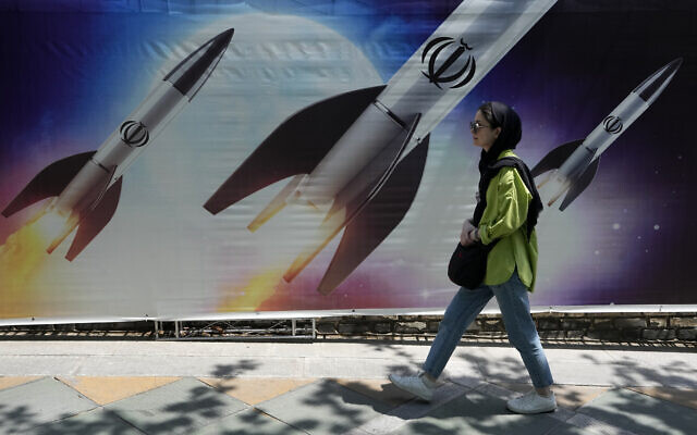 A woman walks past a banner showing missiles being launched, in northern Tehran, Iran, April 19, 2024. (AP Photo/Vahid Salemi)