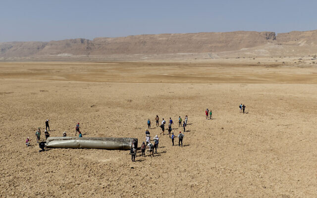 People gather around a component from an intercepted ballistic missile fired by Iran on April 14, 2024 that fell near the Dead Sea, April 20, 2024 (AP Photo/Itamar Grinberg)