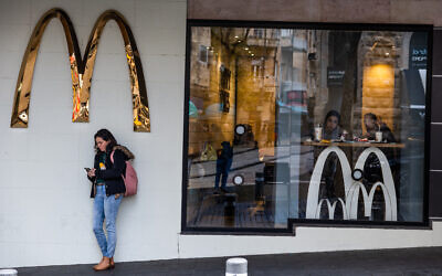 File: A woman standing under a McDonald's sign, in central Jerusalem, February 2, 2023. (Nati Shohat/Flash90)