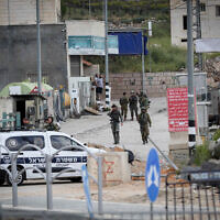 Israeli troops stand guard near the scene of a shooting, near Hebron in the West Bank, April 21, 2024. (Wisam Hashlamoun/ FLASH90)