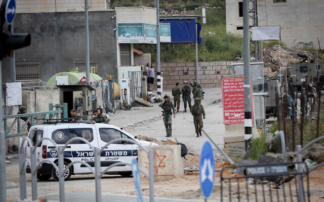 Israeli troops stand guard near the scene of a shooting, near Hebron in the West Bank, April 21, 2024. (Wisam Hashlamoun/ FLASH90)