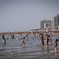 People enjoy the beach in Tel Aviv during a heatwave, on April 24, 2024. (Avshalom Sassoni/Flash90)