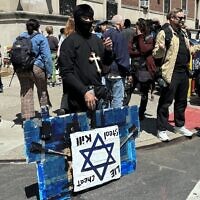 A masked protestor near the Columbia University campus in New York City with a sign bearing a Star of David and the words 'Lie, Cheat, Steal, Kill,' April 25, 2024. (Cathryn J. Prince)