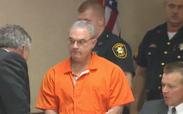 Rabbi Fred Neulander, incarcerated for hiring two hitmen to murder his wife Carol in 1994, is shown here in prison uniform from undated, unlocated footage in prison uniform, escorted by police. (Screen capture: Youtube/6ABC Philadelphia, used in accordance with Clause 27a of the Copyright Law)